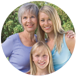 Grandmother, mother and granddaughter smiling outside.