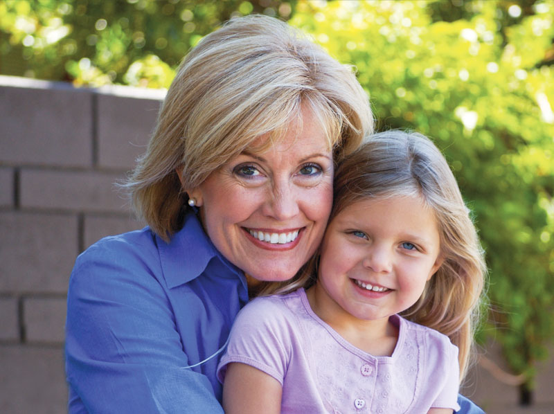 Grandmother and granddaughter smiling outside.